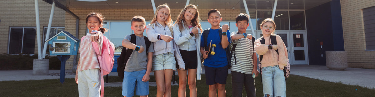 Kids in front of a school displaying SafeOwl watch on their wrists